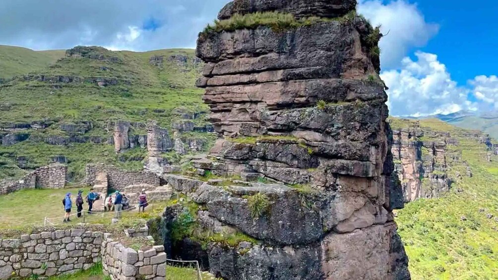 A rocky cliff with ruins and a grassy landscape. 2