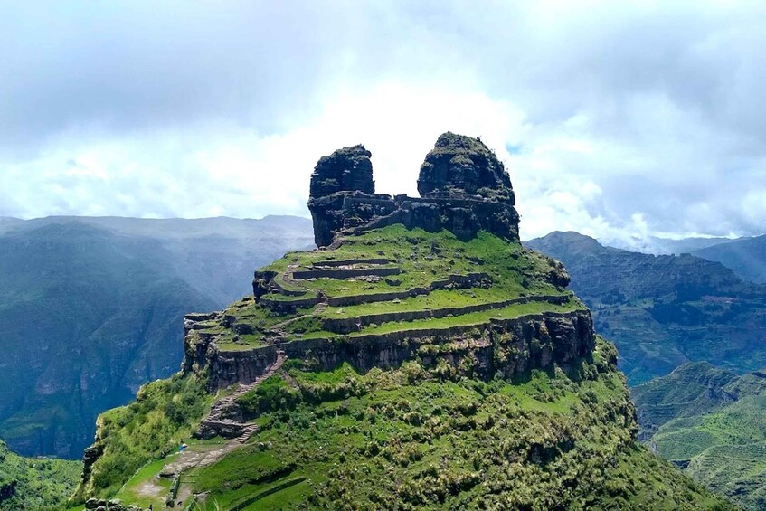 A mountainous landscape with terraced structures and two prominent rock formations. 1