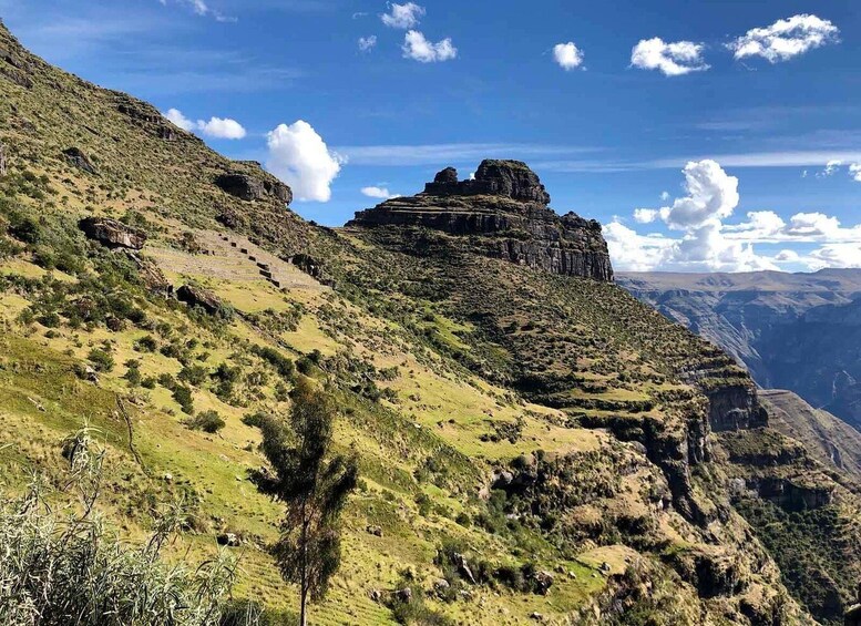 A mountainous landscape with a prominent rock formation and terraced fields. 4