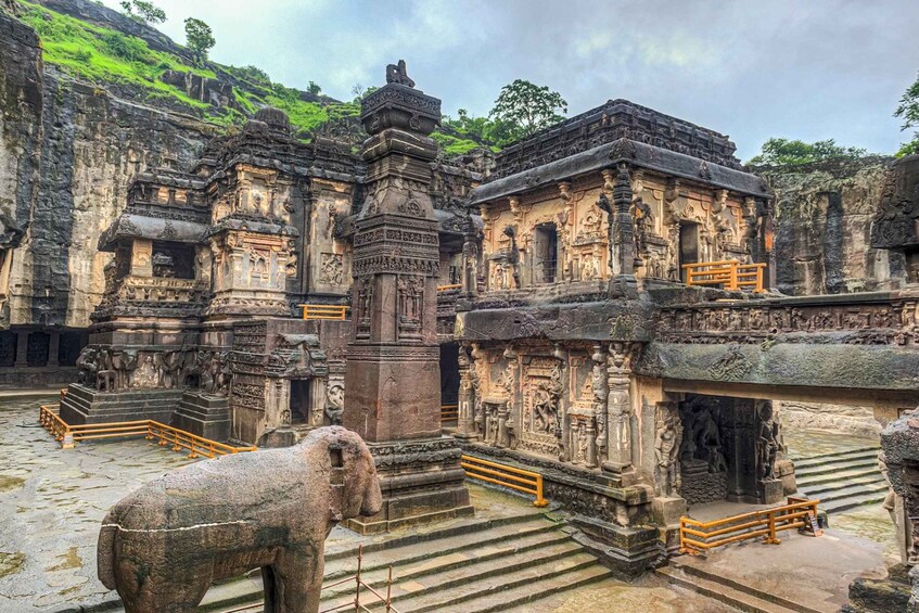 Ancient stone structures with intricate carvings, a stone elephant, and a staircase leading to a temple entrance. 1