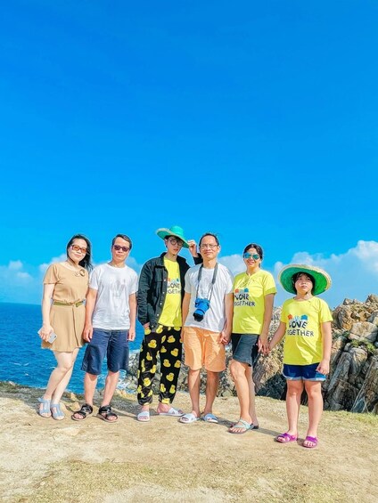 A group of people standing on a rocky shore with the ocean in the background. 3