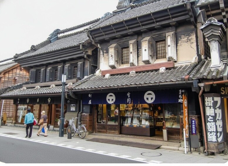 A traditional Japanese street with wooden buildings, a bicycle, and pedestrians. 2