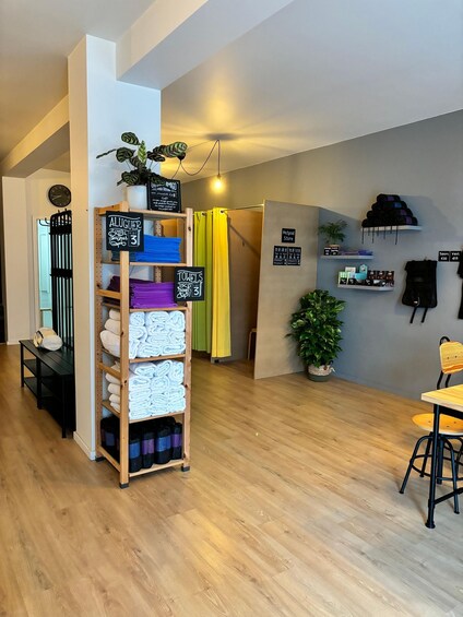 A cozy indoor space with a wooden floor, a shelf with folded towels, a chalkboard sign, and a wall-mounted shelf with items. 3