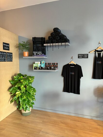 A store interior with black clothing, a plant, and a sign indicating prices. 4