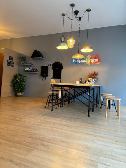 A modern interior with a dining area, wooden flooring, and a wall sign reading 'hotpod yoga'. 2