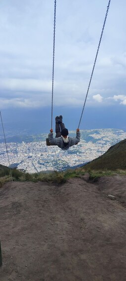 A person on a swing overlooking a cityscape. 4