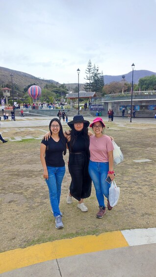 Three people walking in a park with a hot air balloon in the background. 5