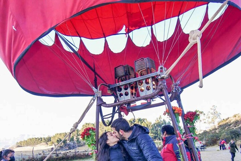 A hot air balloon with a red canopy, a basket with passengers, and a landscape with trees and a clear sky. 2