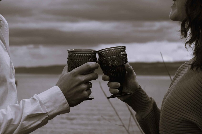 Two people holding wine glasses at a beach. 2