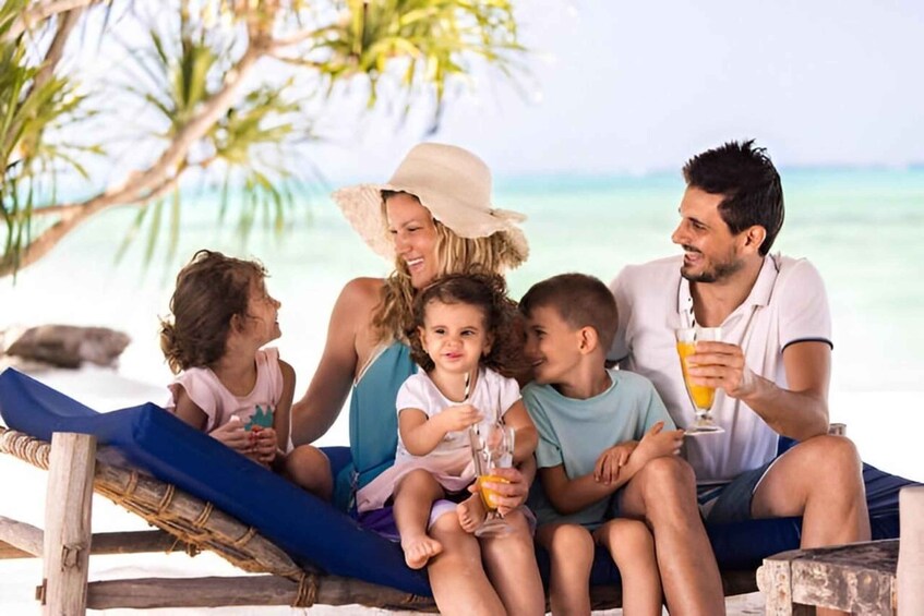 A family of five on a beach with palm trees and ocean in the background. 1