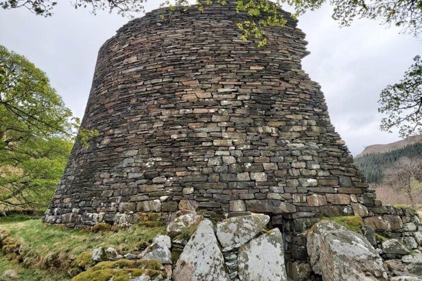 A stone tower with moss-covered stones and a grassy base. 3