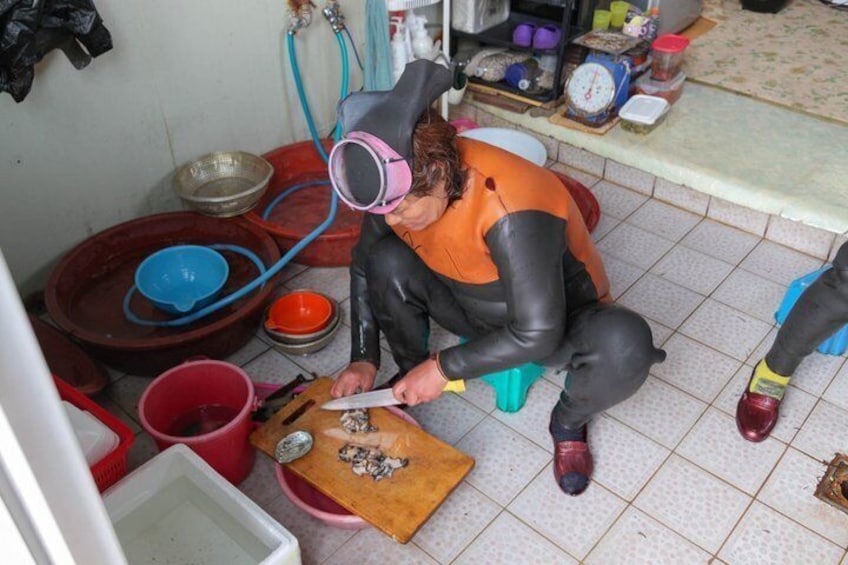 A person in a kitchen, cutting food on a cutting board. 2