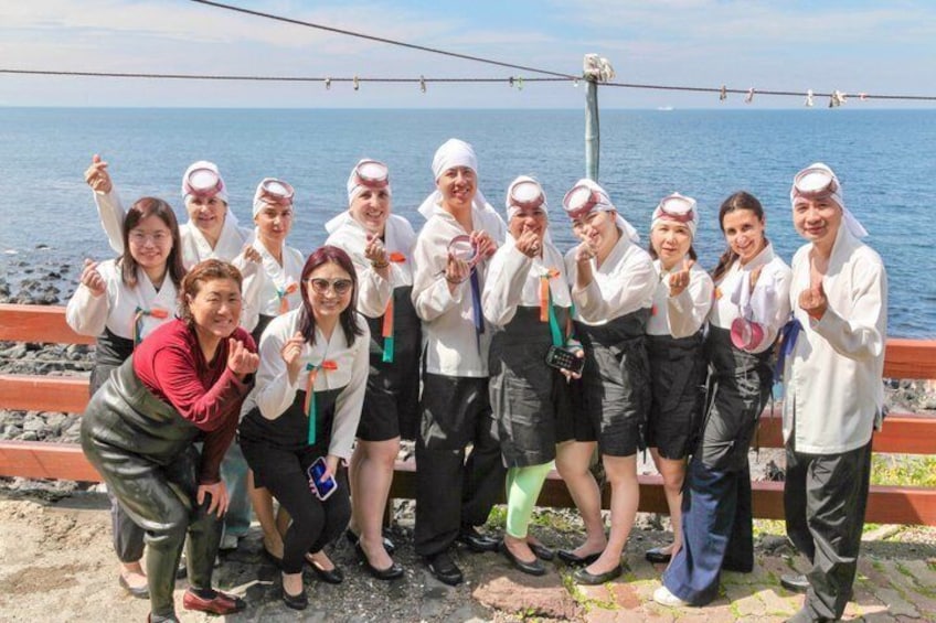 A group of people standing on a rocky shore with the sea in the background. 4
