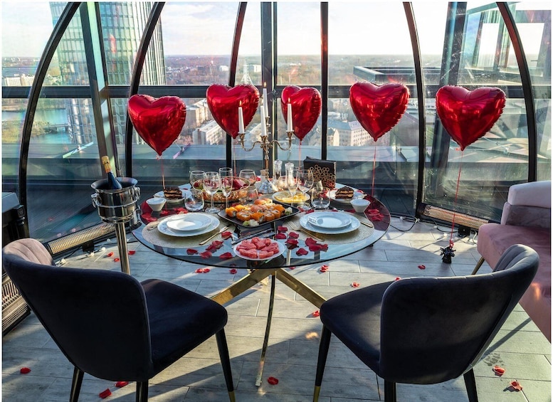 A rooftop dining setup with a table set for two, surrounded by heart-shaped balloons and a champagne bottle. 4