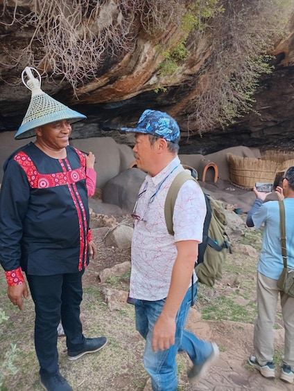 Two people walking outdoors, one wearing a patterned hat and the other with a backpack. 3