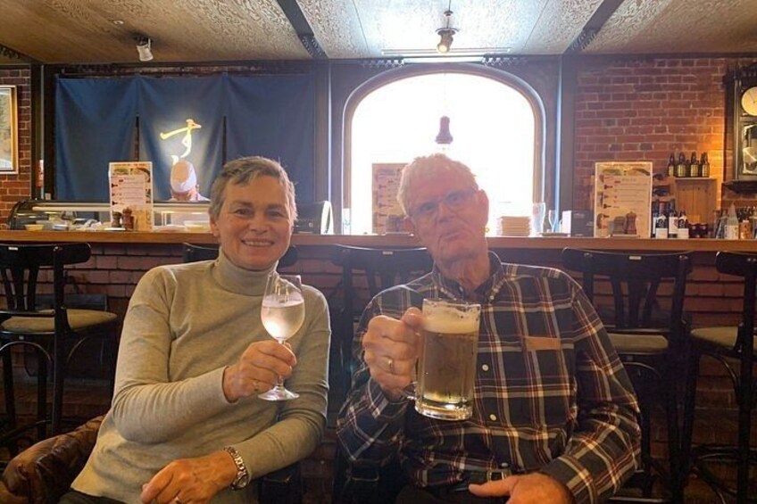 Two people sitting at a bar, one holding a glass of wine and the other holding a glass of beer. 3