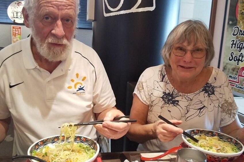 Two people eating noodles with chopsticks. 2
