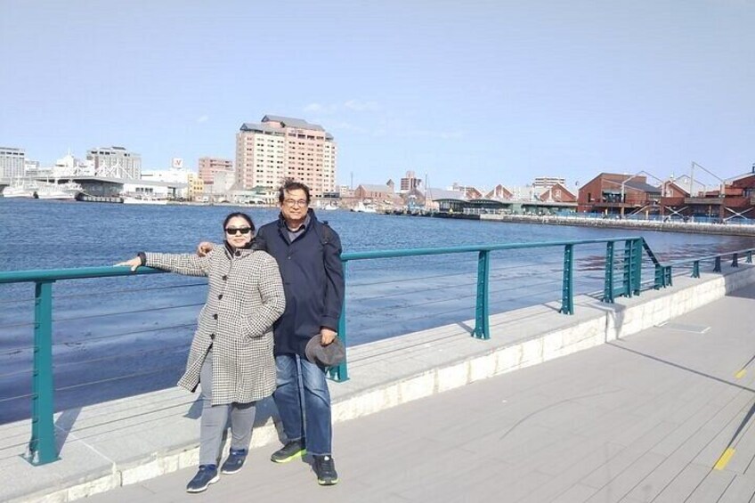 A waterfront promenade with a railing, a body of water, and buildings in the background. 4