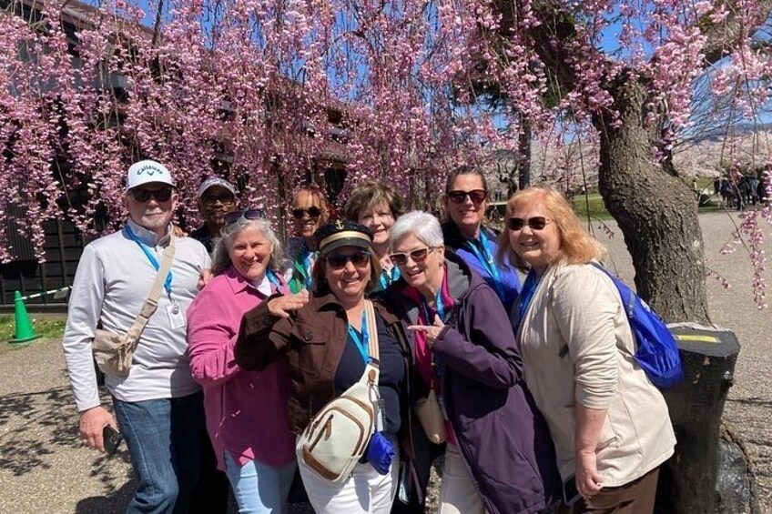 A group of people posing in front of cherry blossom trees. 4