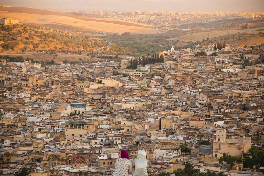 A densely packed urban landscape with a prominent hill in the background. 1