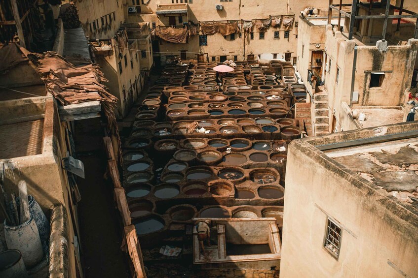 A traditional tannery with large vats of dyeing materials, narrow walkways, and old buildings with laundry hanging outside. 2