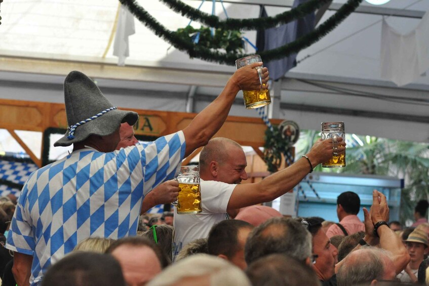 A crowd at an outdoor event, possibly a festival, with people holding beer mugs. 3
