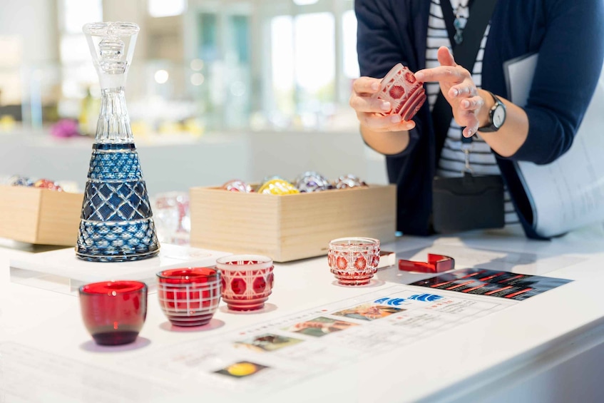 A person examining a card at a table with various glassware and a decorative bottle. 1