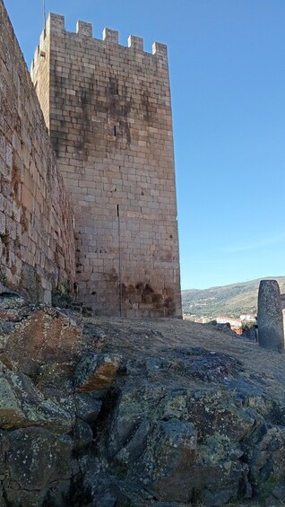 A stone castle wall with a clear sky in the background. 3