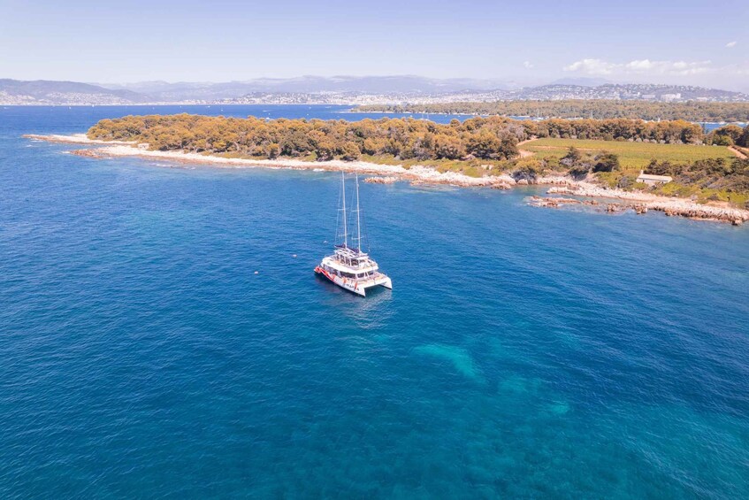 A white sailboat with a cabin and a mast, anchored in clear blue waters. 5