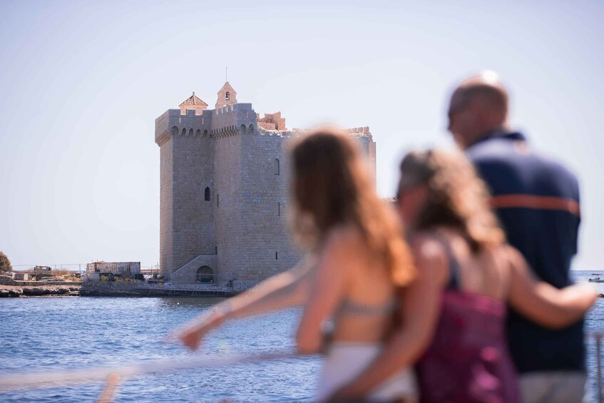A castle by the sea with tourists in the foreground. 2