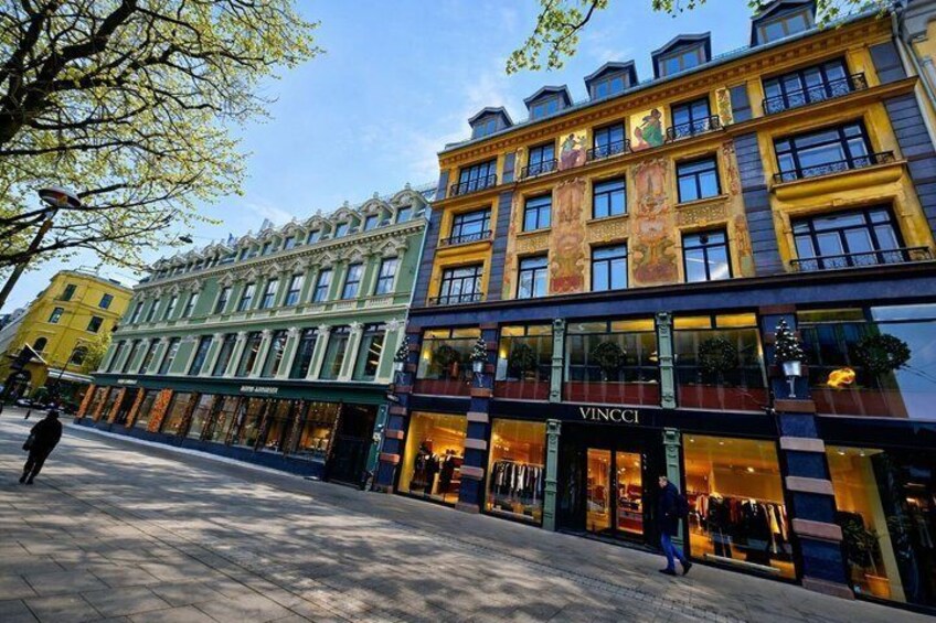 A street with a building labeled 'VINCCI' and another building with a green facade. 5
