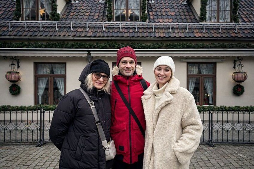 Three people standing in front of a building with a tiled roof and a fence. 2