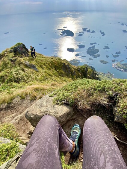 A hiker's legs and feet on a grassy hill overlooking a body of water with islands. 3