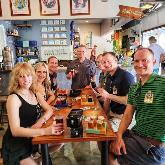 A group of people seated at a bar with various beer taps and a menu board in the background. 1