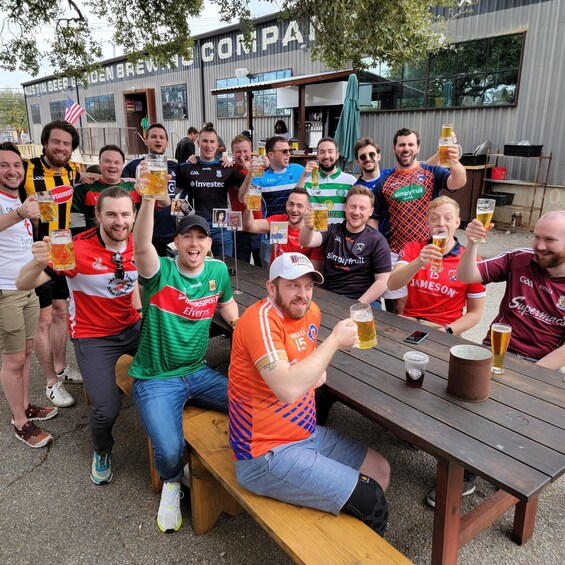 A group of people at an outdoor gathering, some holding beer mugs, with a building labeled 'Austin Seerland Brewery' in the background. 3