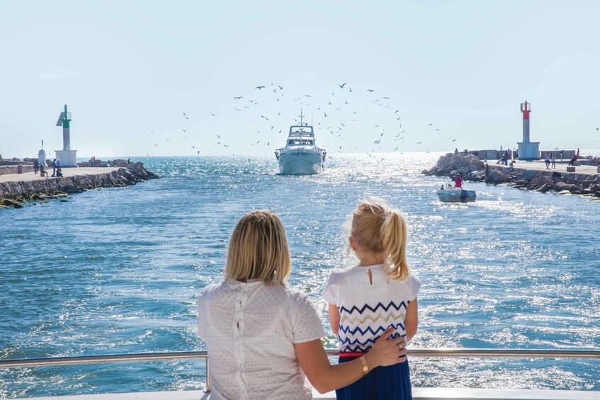A boat on the water with lighthouses and people on the shore. 1