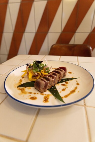 A plate of food with a blue rim, placed on a white tiled table. 2