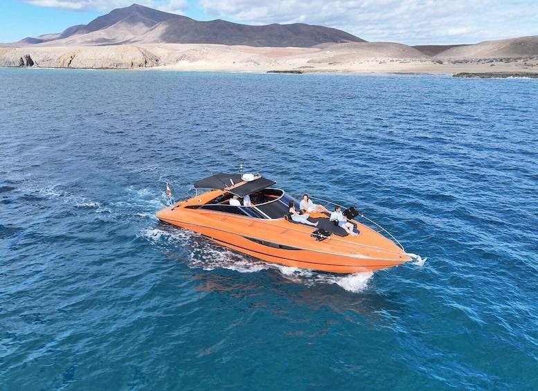 An orange speedboat on a calm sea with a mountainous landscape in the background. 1