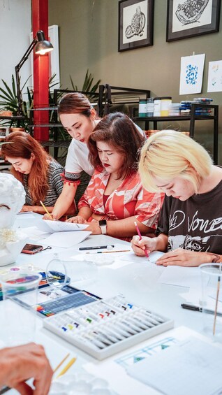 A group of people engaged in a drawing activity at a table with art supplies. 4