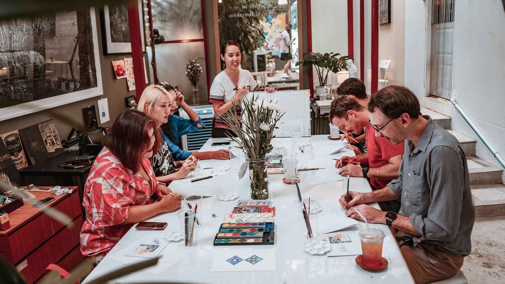 A group of people engaged in a painting activity at a table with art supplies. 1