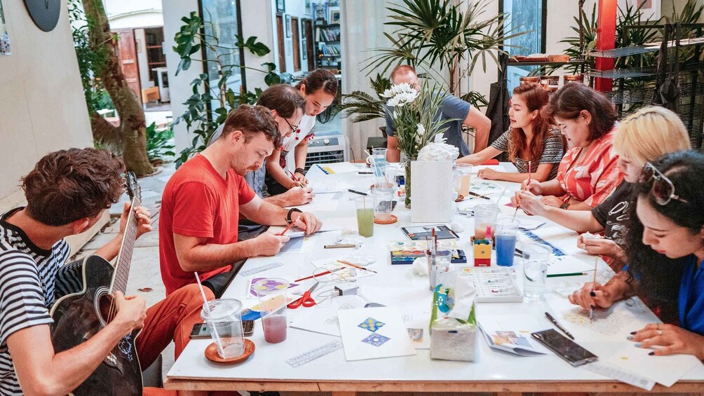 A group of people engaged in a painting activity around a table with art supplies. 3