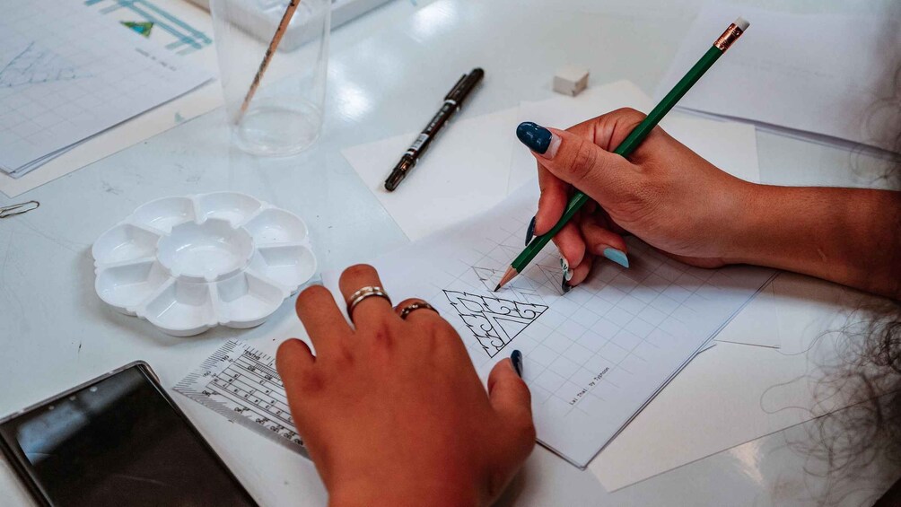 A person drawing geometric shapes on graph paper with a pencil. 5