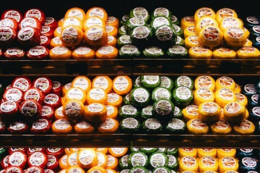 A cheese display with various types of cheese in red, yellow, and green packaging. 5