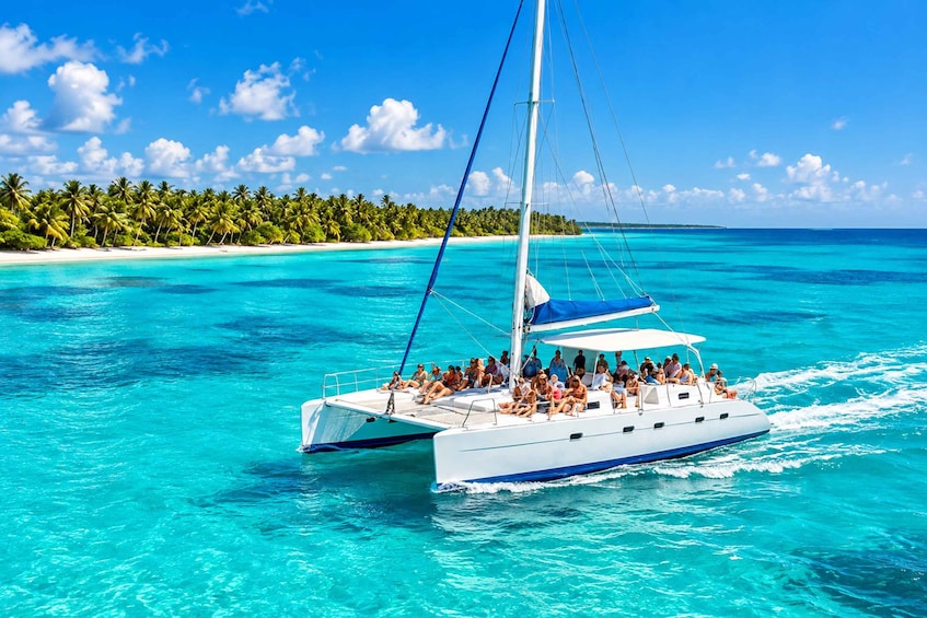 A sailboat with passengers on a turquoise sea, surrounded by a tropical island with palm trees. 4