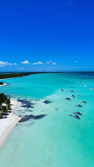 A turquoise sea with boats and a white sandy beach. 1