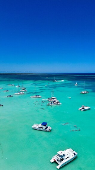 A turquoise sea with numerous boats and yachts anchored, under a clear blue sky. 5