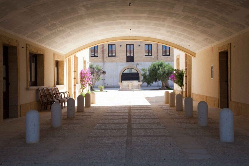 An arched corridor with a bench, bollards, and a building in the background. 5