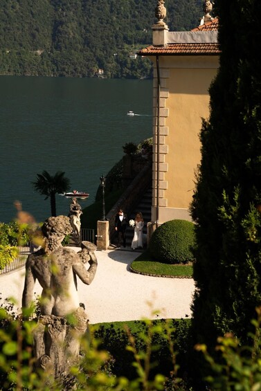 A lake with a boat, a statue, and a building with a balcony. 5