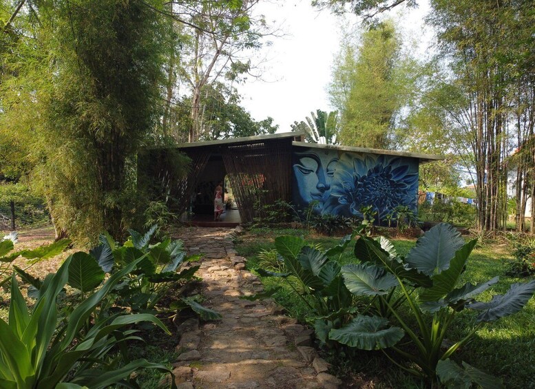A garden pathway leading to a structure with a mural. 2