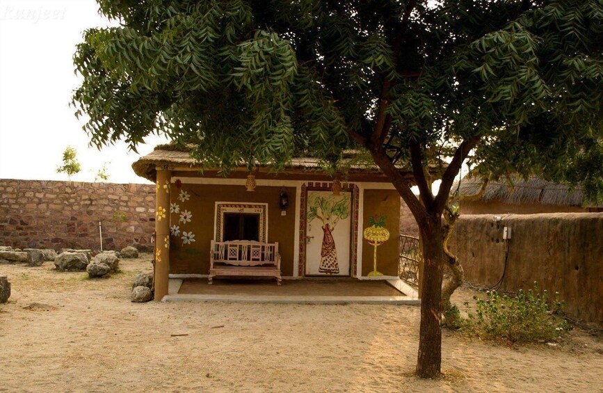 A traditional building with a thatched roof, a bench outside, and a tree in front. 5